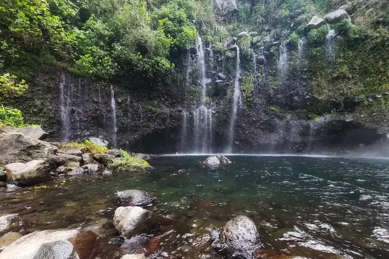 Cascade et bassin de baignade dans la rivière, roches volcaniques et végétation